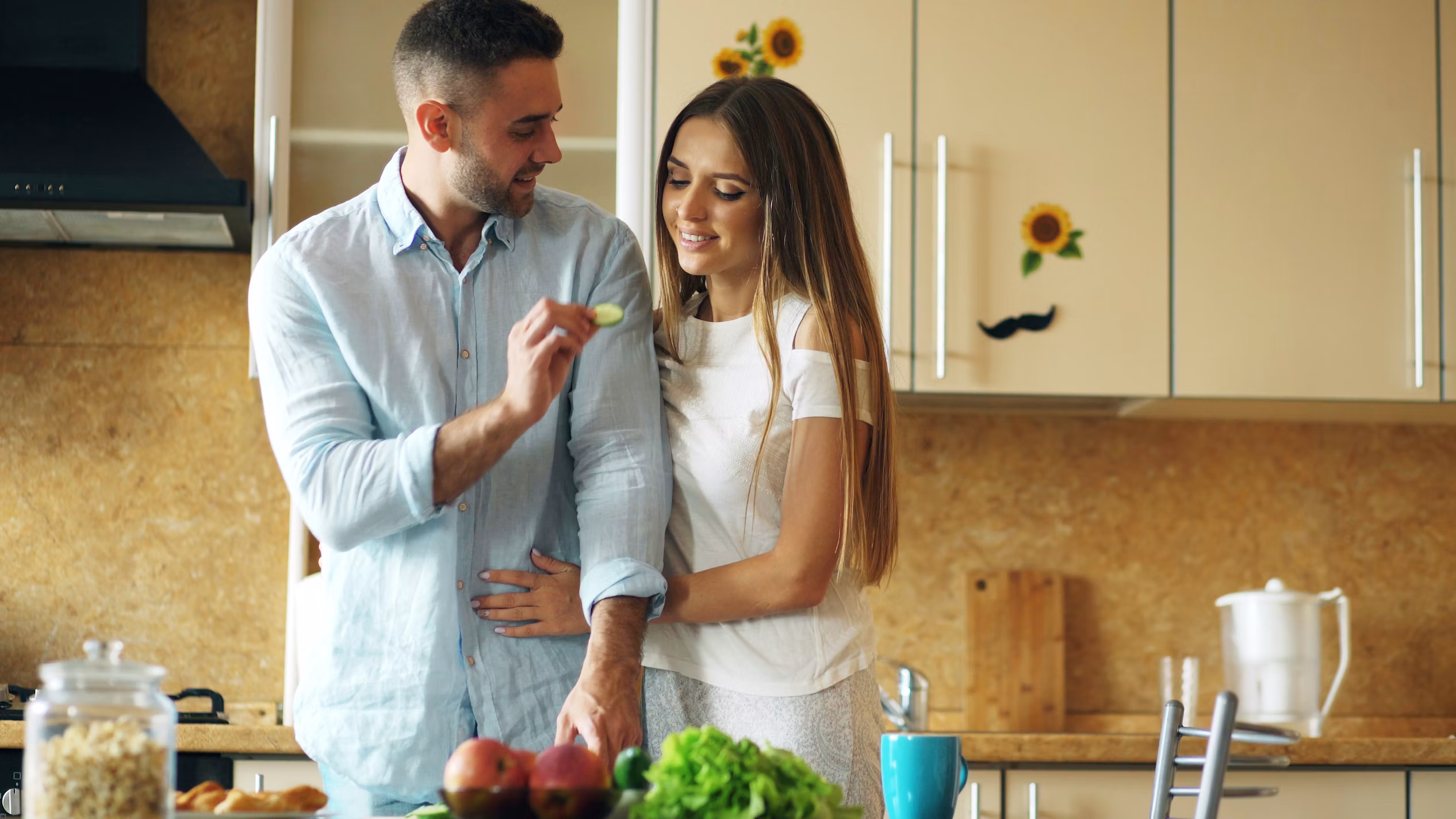 couple souriant en cuisine préparant un repas